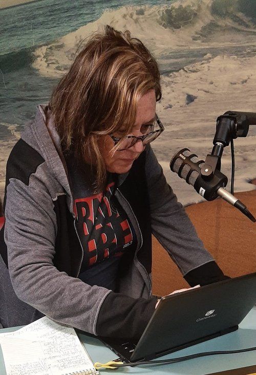 A woman sitting at a desk with a laptop and a microphone