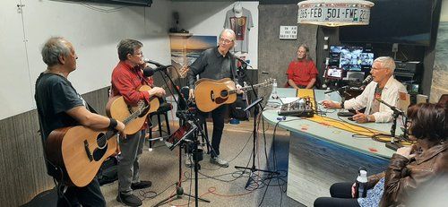 A group of men are playing guitars and singing into microphones in a room.