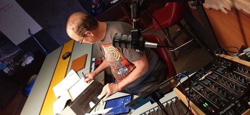 A man is sitting at a desk in front of a microphone.