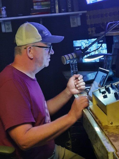 A man in a purple shirt is sitting in front of a microphone