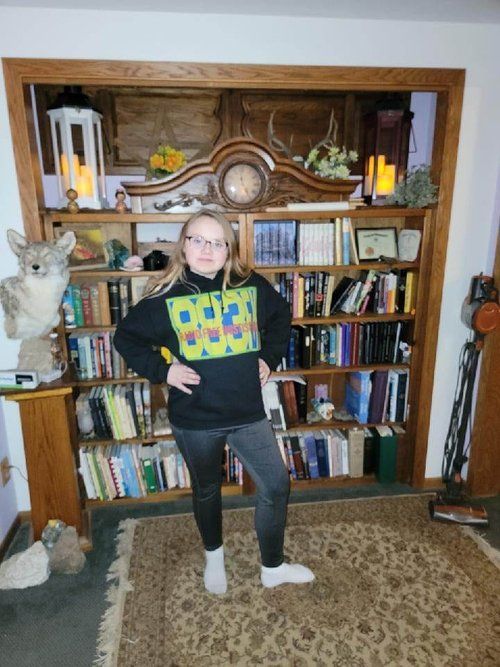 A woman is standing in front of a bookshelf in a living room.
