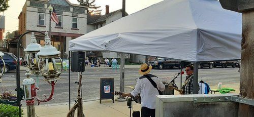 A man is playing a guitar under a white tent.
