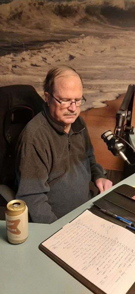 A man is sitting at a desk with a can of beer and a notebook.