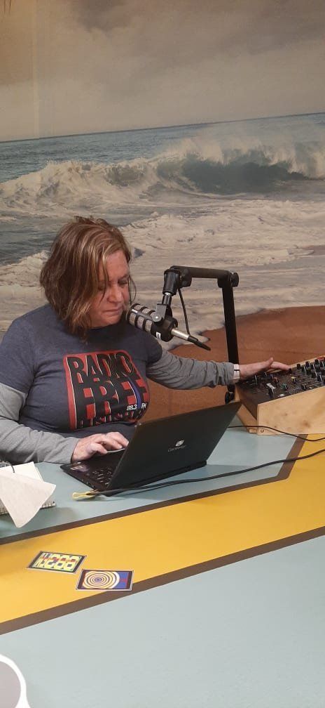 A woman is sitting at a desk with a laptop and a microphone.
