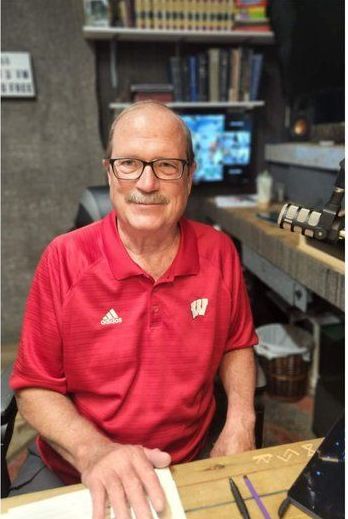 A man wearing a red adidas shirt sits at a desk
