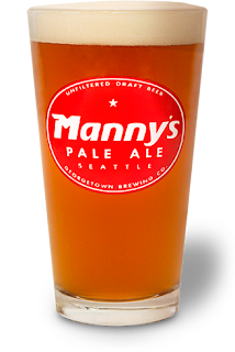 Pint glass of amber Monny’s Pale Ale with a foamy head on a white background