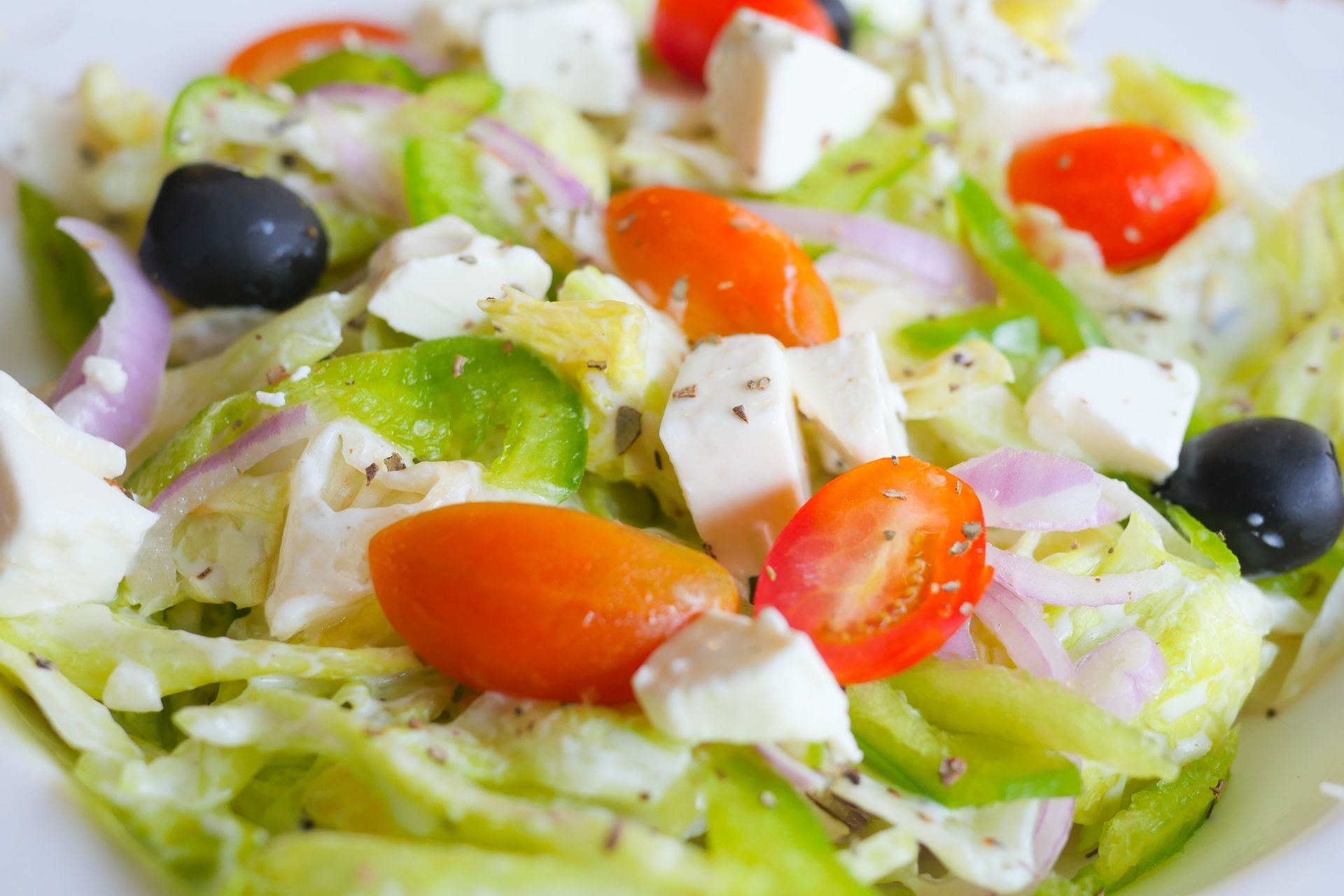 Greek salad with lettuce, cucumber, cherry tomatoes, olives, feta, and onions