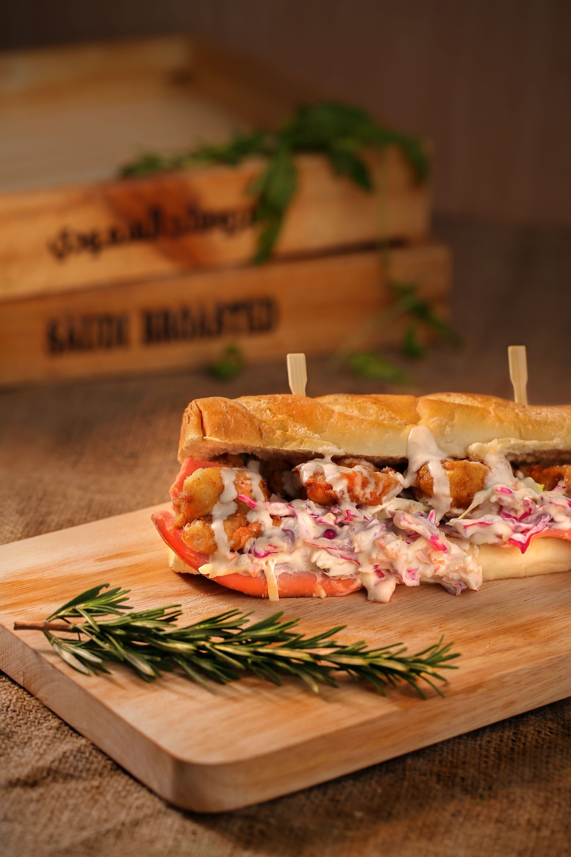 Toasted sandwich with creamy filling and rosemary on a wooden board