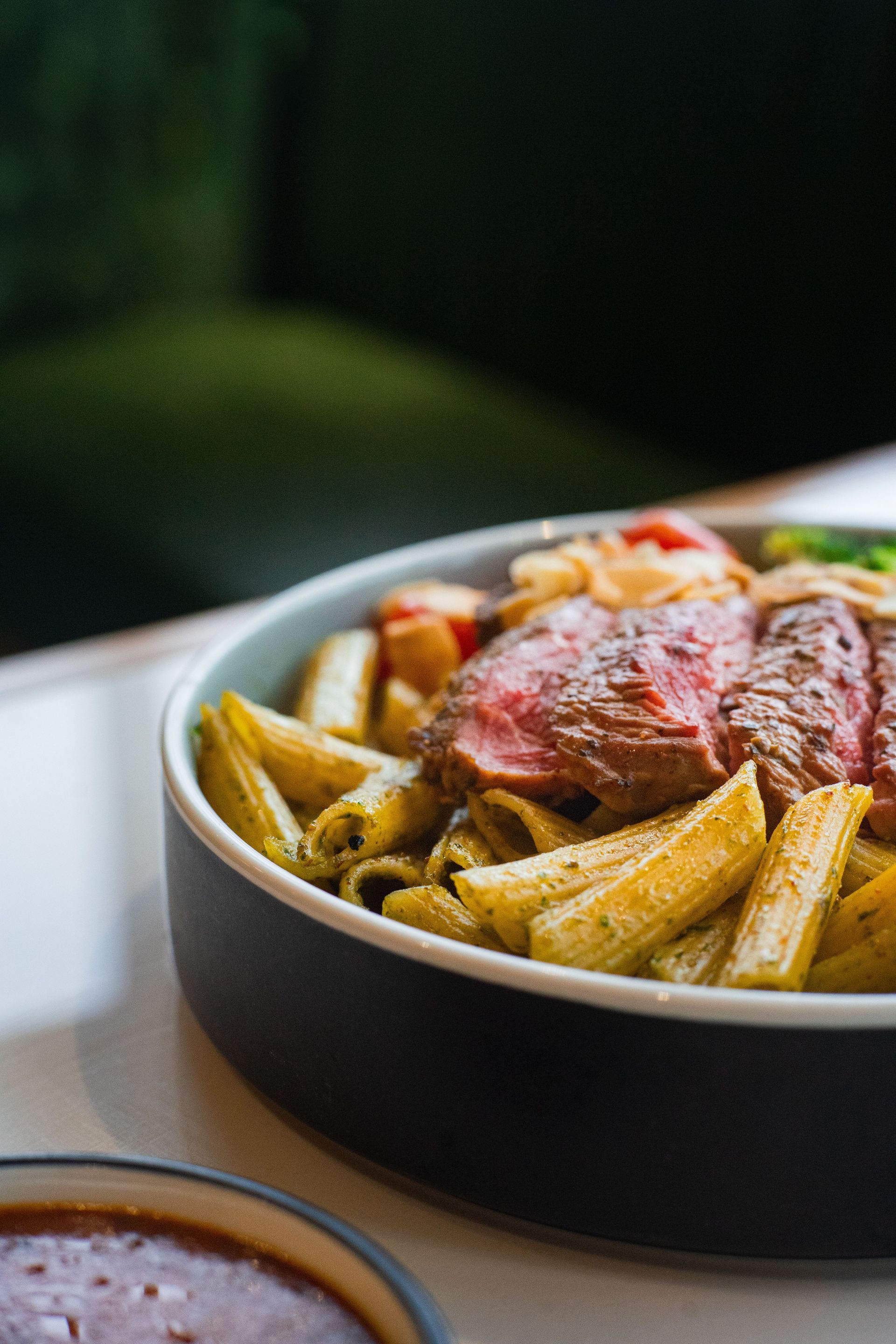 Steak with seasoned fries in a black bowl on a table, with a blurred background