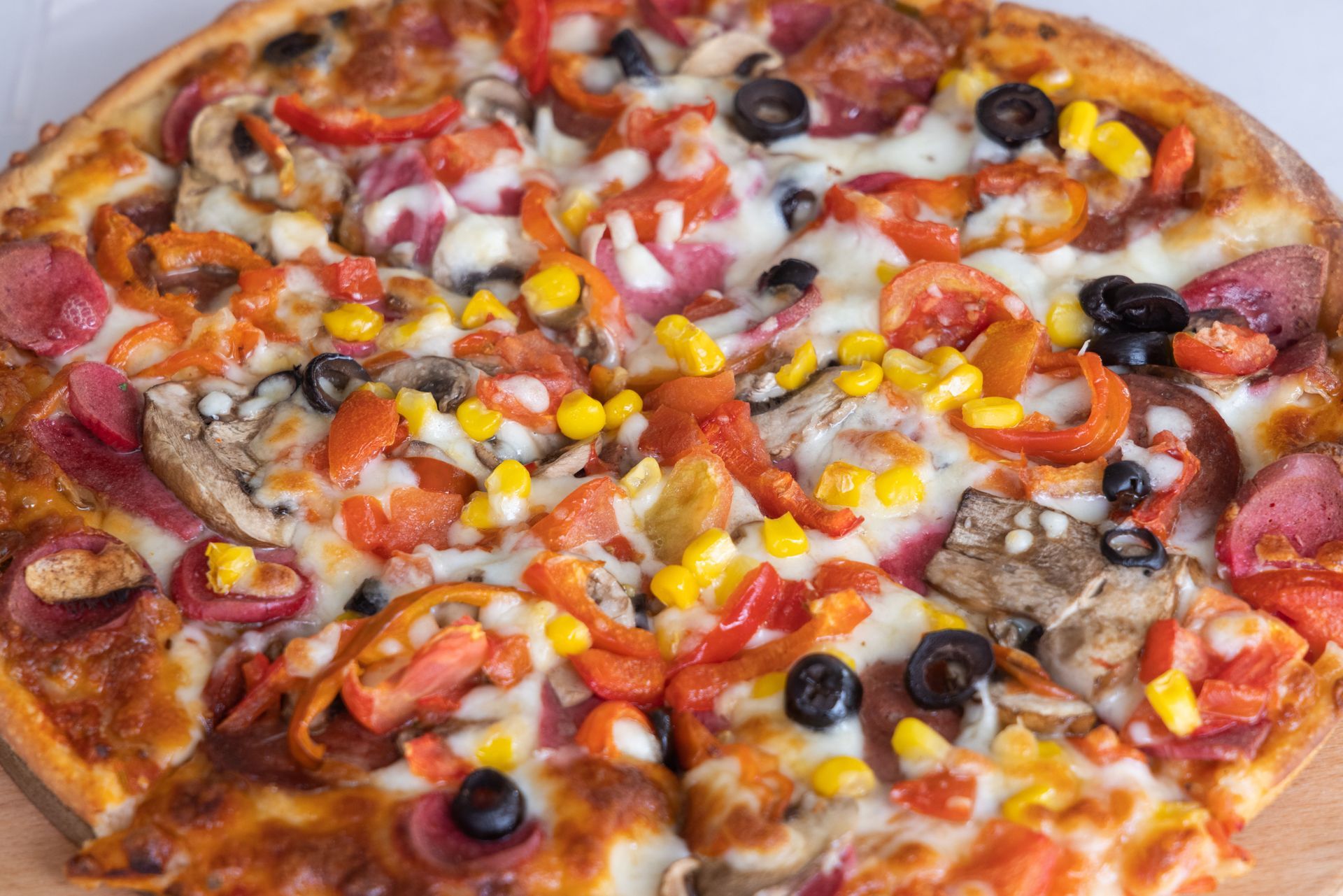 Vegetable pizza topped with olives, corn, mushrooms, tomatoes, and melted cheese