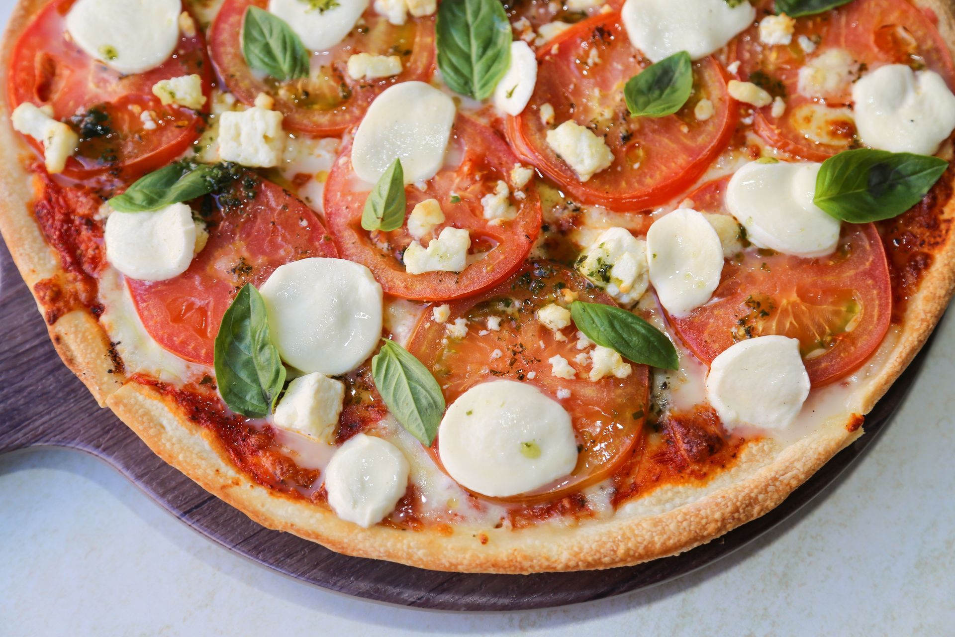 Margherita pizza with mozzarella, basil, and tomato on a wooden board