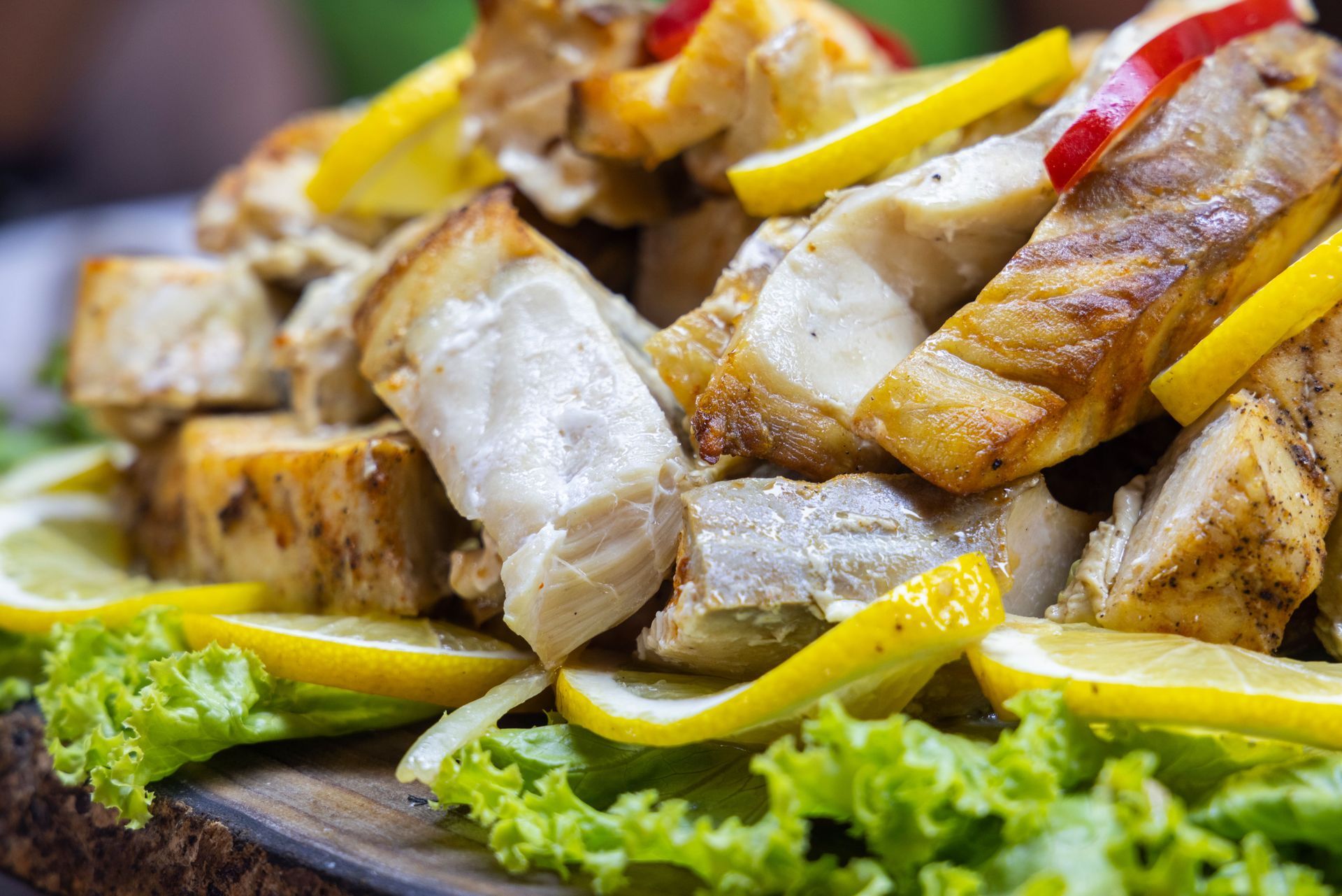 Grilled fish fillets with lemon wedges and lettuce on a serving platter