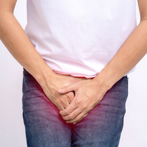 Un hombre se sostiene la parte inferior del abdomen con las manos.