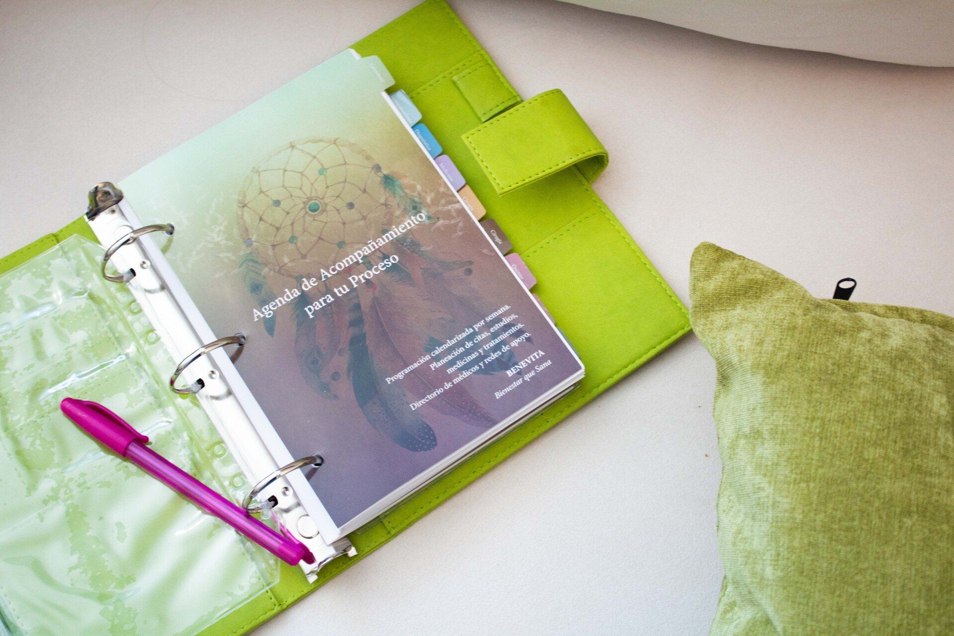 A green binder with a pink pen and a green pillow