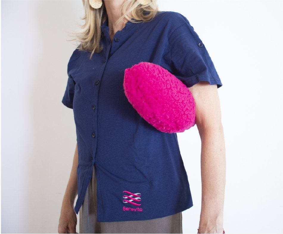 A woman in a blue shirt is holding a pink pillow