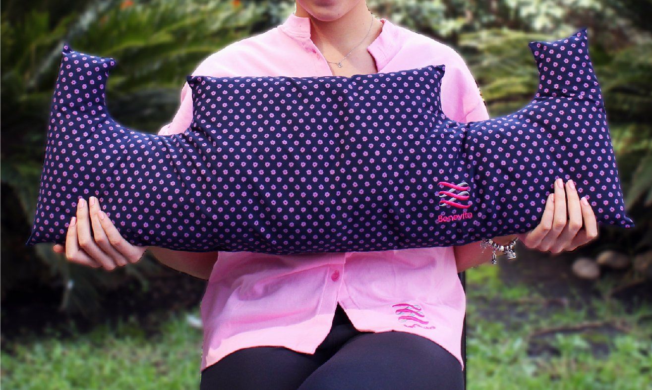 A woman in a pink shirt is holding a blue pillow in her hands.