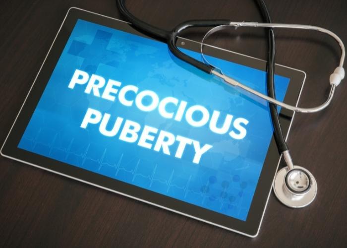 Tableta que muestra “PUBERTAD PRECOZ” con un estetoscopio sobre un escritorio.