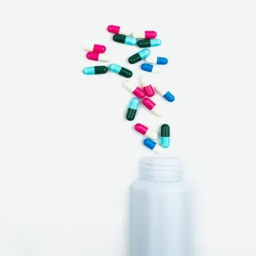 Cápsulas saliendo de un frasco: ilustración de un medicamento oral en cápsulas, como el crizotinib