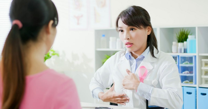 Un médico habla con un paciente en una luminosa consulta, gesticulando mientras sostiene un portapapeles.