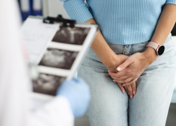 El paciente se sujeta la ingle mientras habla con un médico que revisa las imágenes de rayos X.