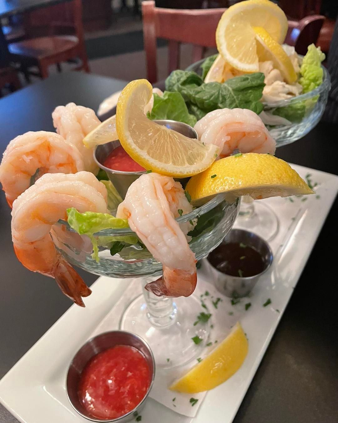 A plate of shrimp cocktail with lemon slices and lettuce