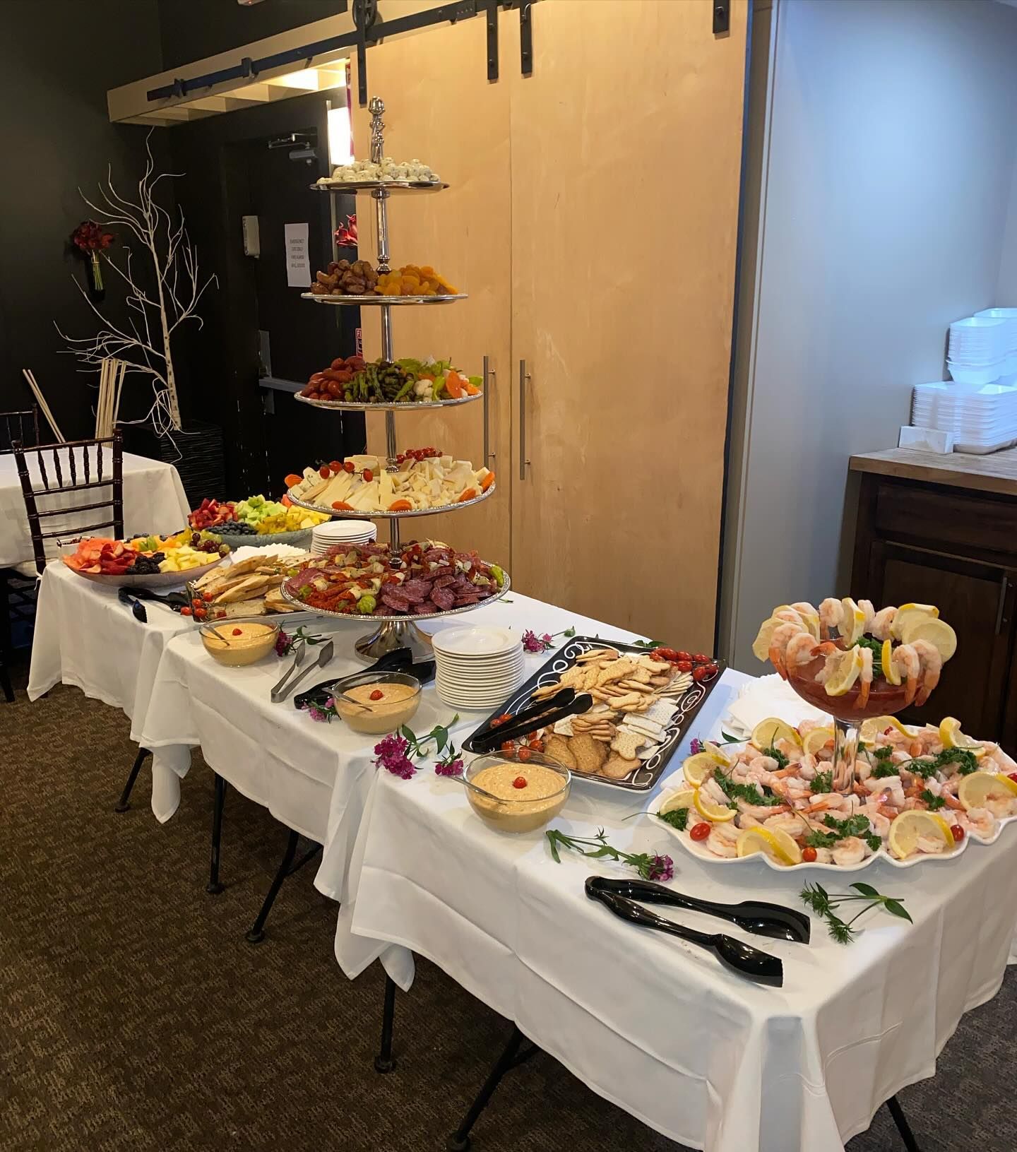 A buffet table with plates of food and tongs on it.