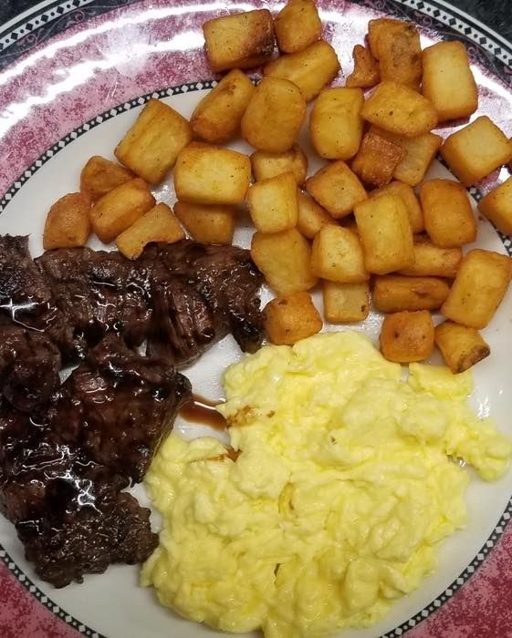 A plate of food with eggs potatoes and meat on it