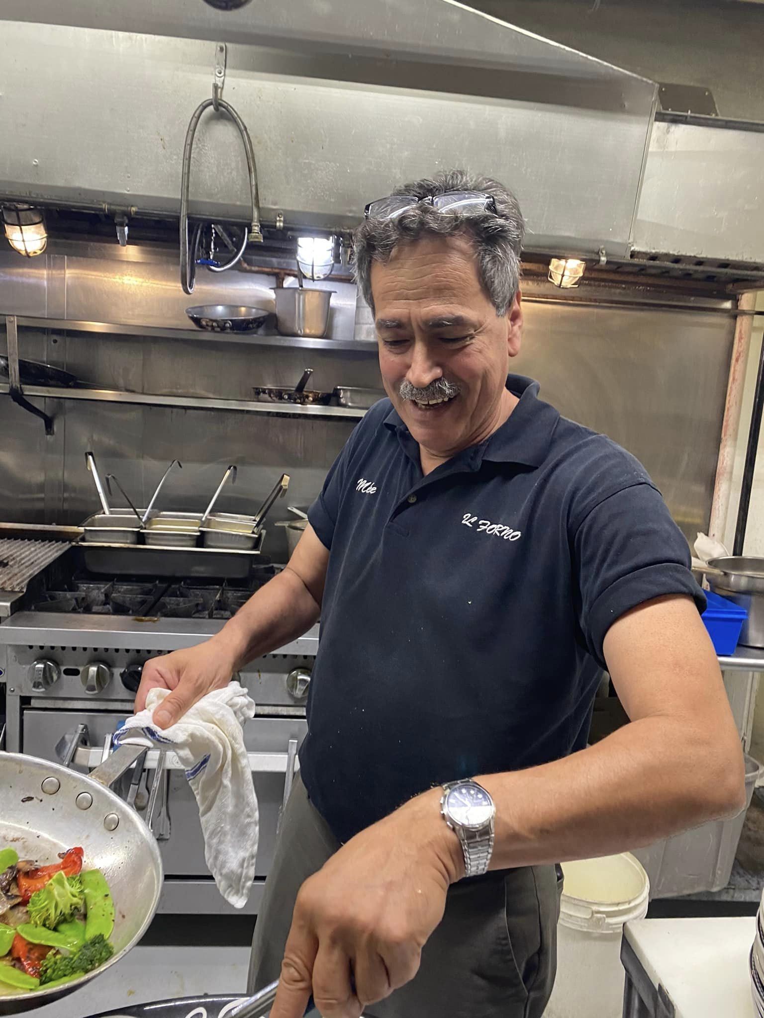 A man in a blue shirt is cooking in a kitchen.