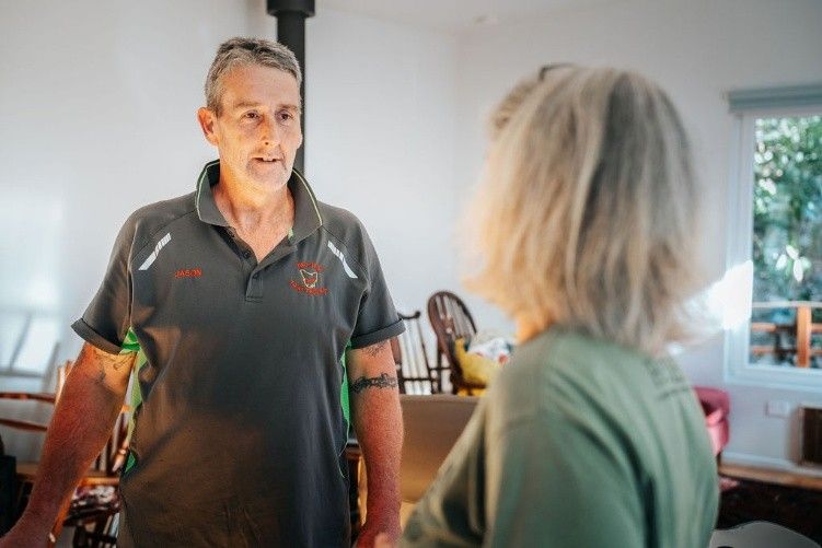 A moving professional in a green shirt converses with a client, both engaged in conversation.