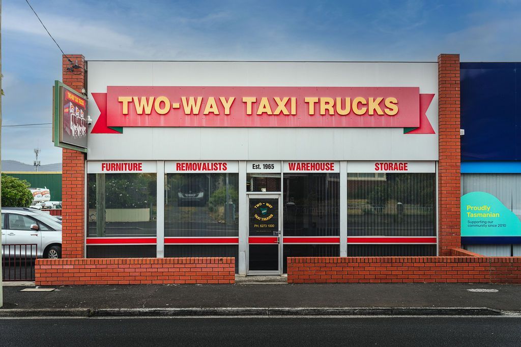 Two-way taxi trucks storefront with red sign, white facade, and large front windows