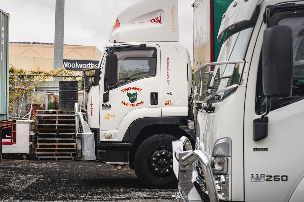 White semi-trucks parked in a lot, one with a red logo and another close-up on the right.