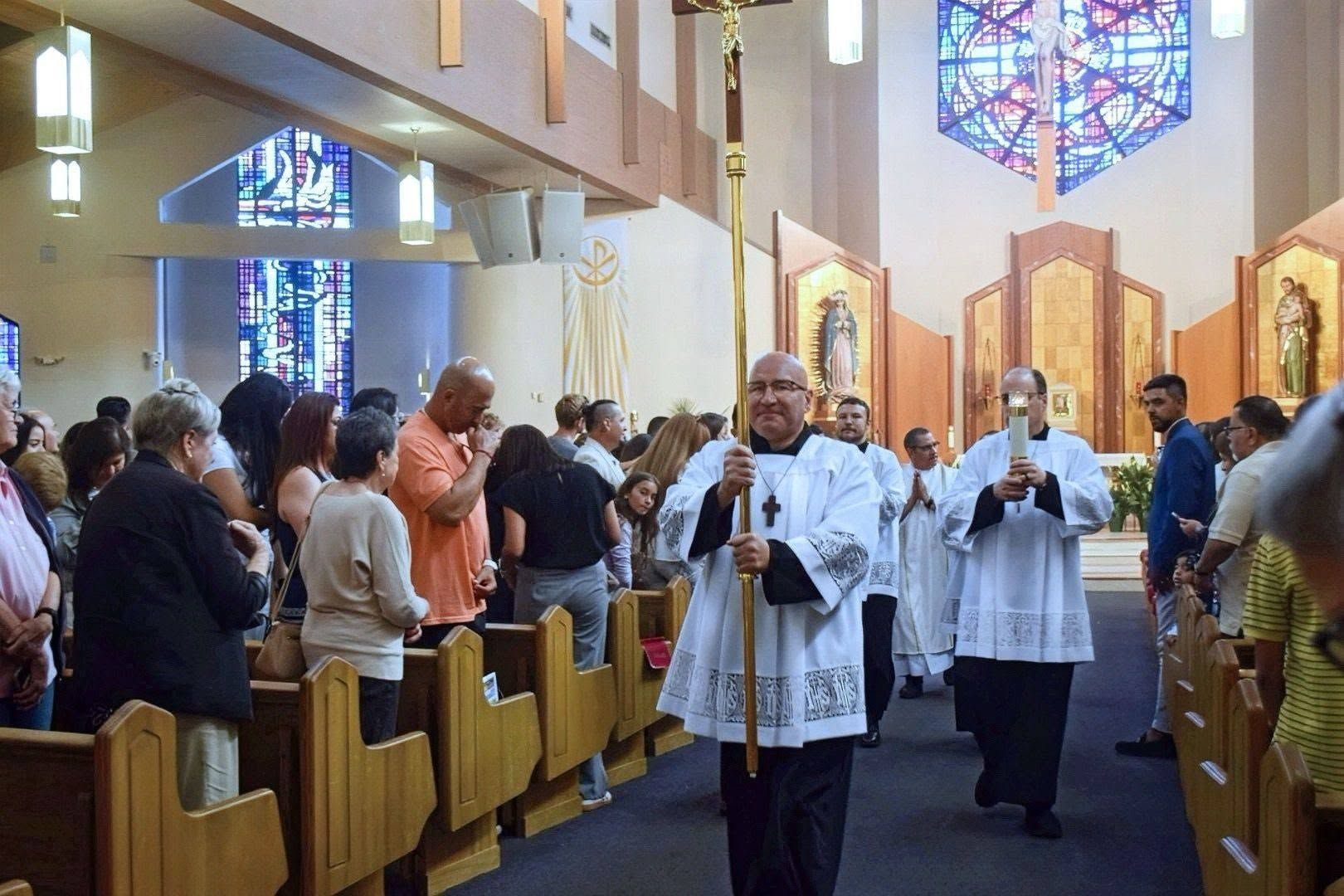 Priests processing down a church aisle during a crowded religious service