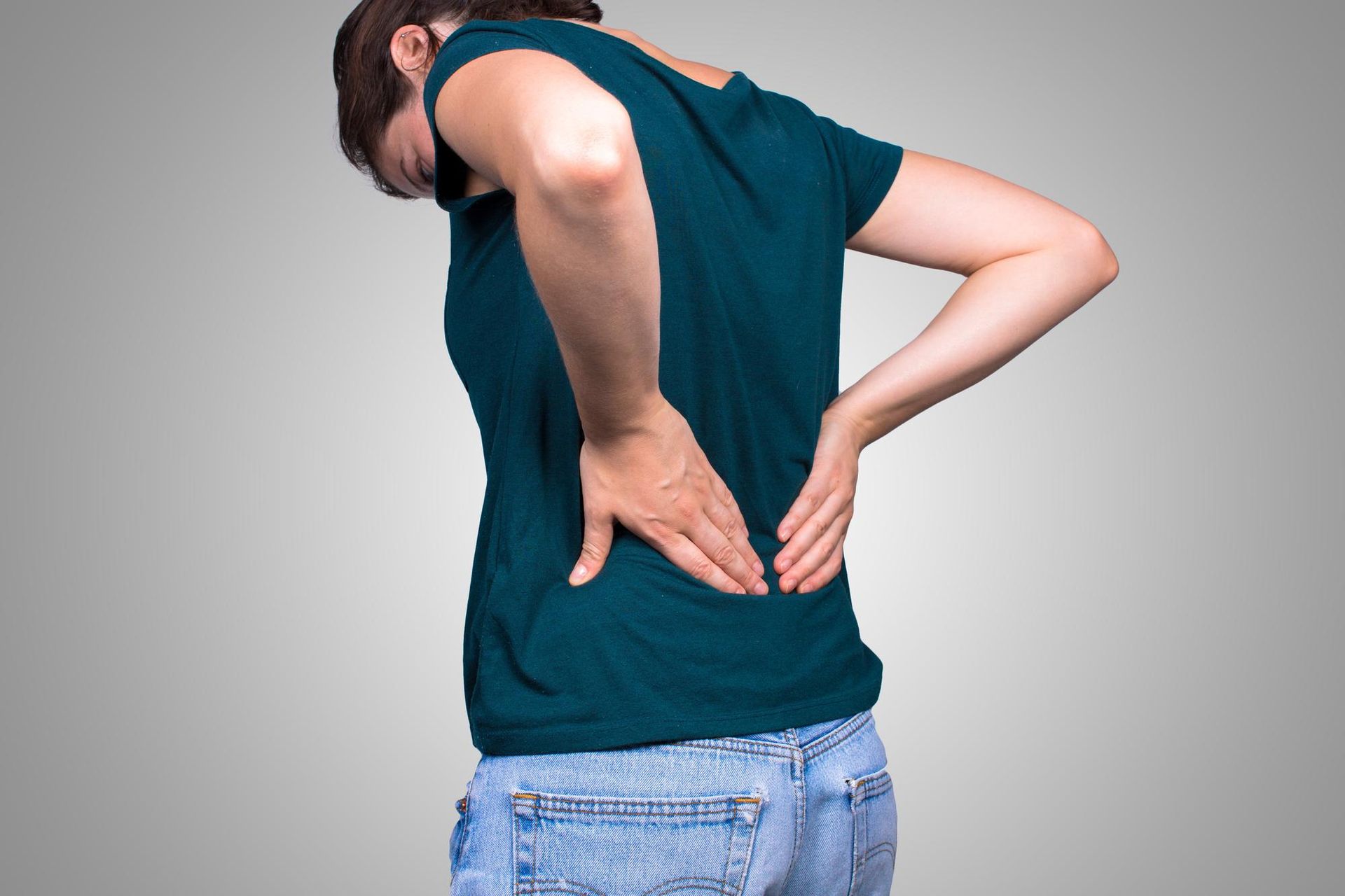 A woman is holding her back in pain.