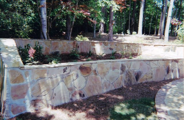 There is a stone wall in the middle of the woods.