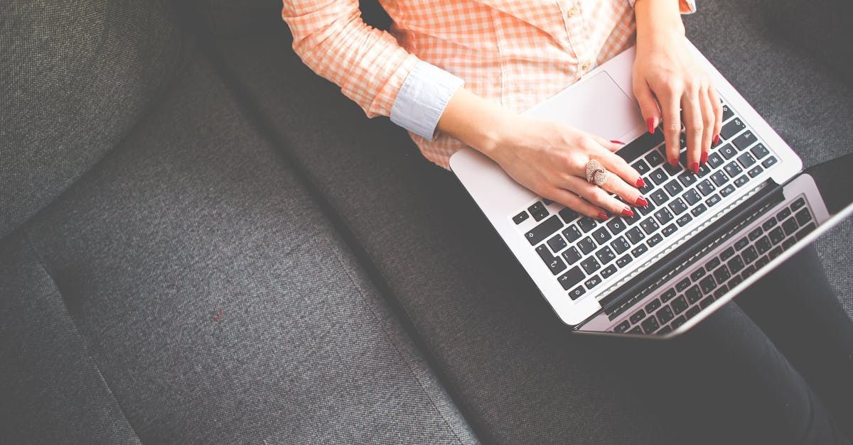 Uma mulher está sentada em um sofá usando um laptop para trabalhar em sua loja