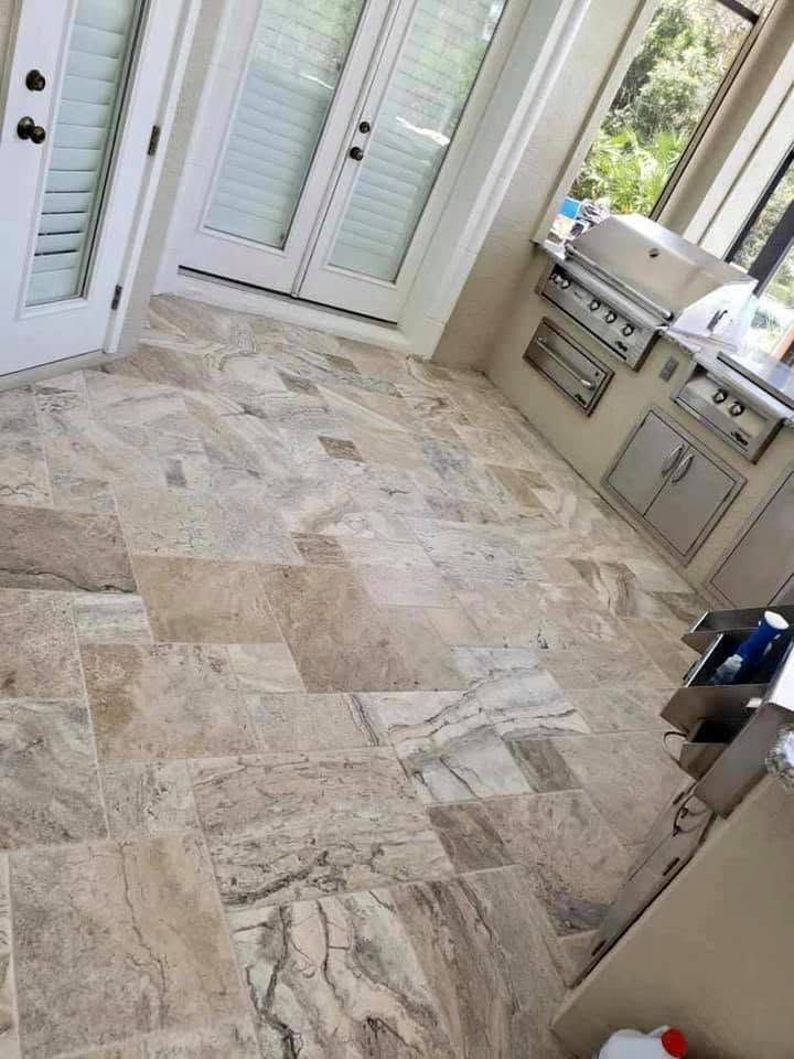 Kitchen with stone tile floor, white French doors, and a stainless steel island sink on the right.