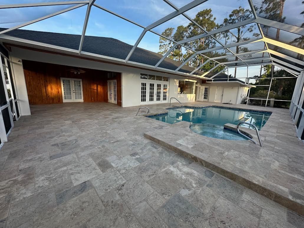Screened backyard patio with brick pavers, a covered pool, and a house with wood siding and white doors