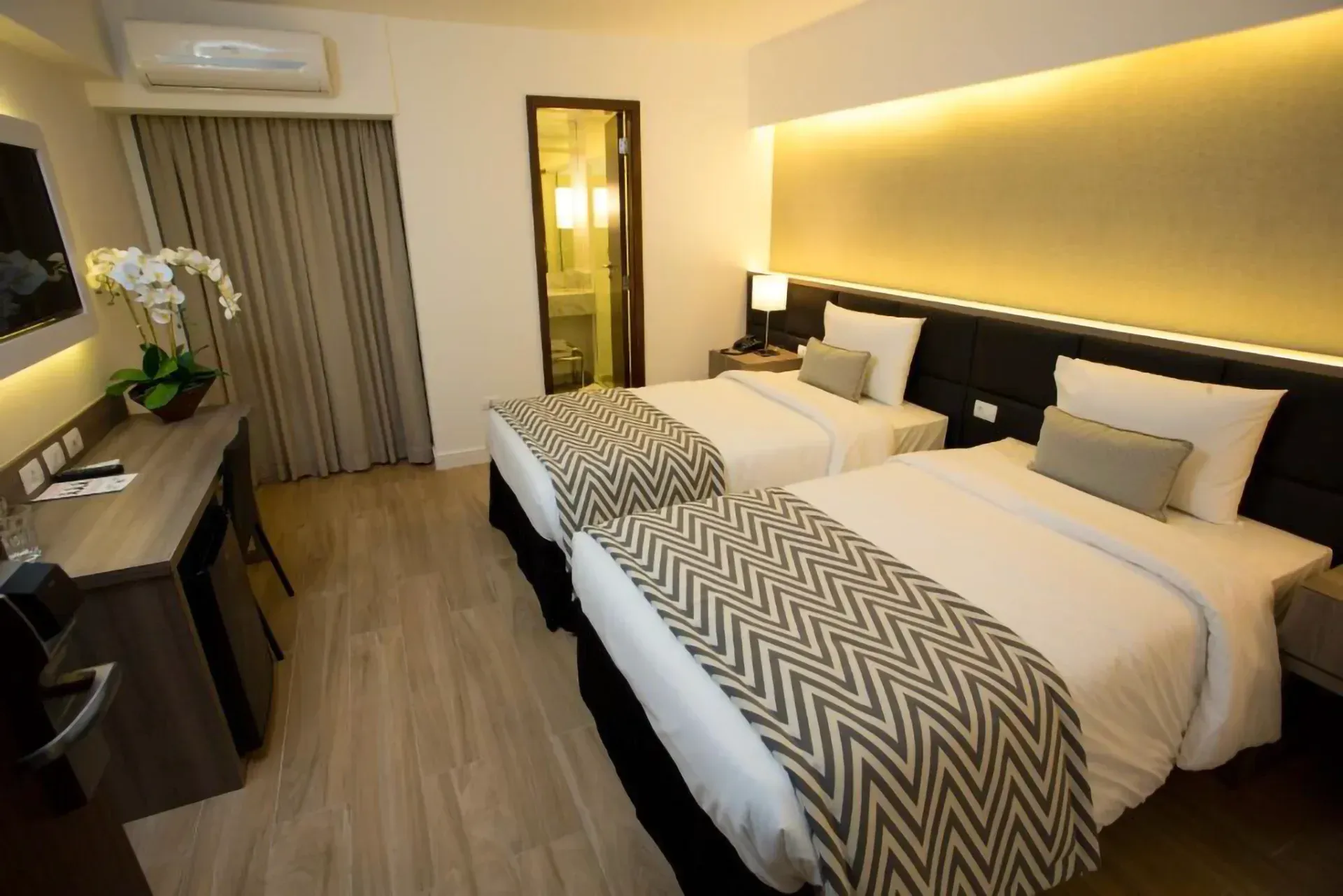 Um quarto de hotel com uma cama grande, escrivaninha, cadeira e luminária.