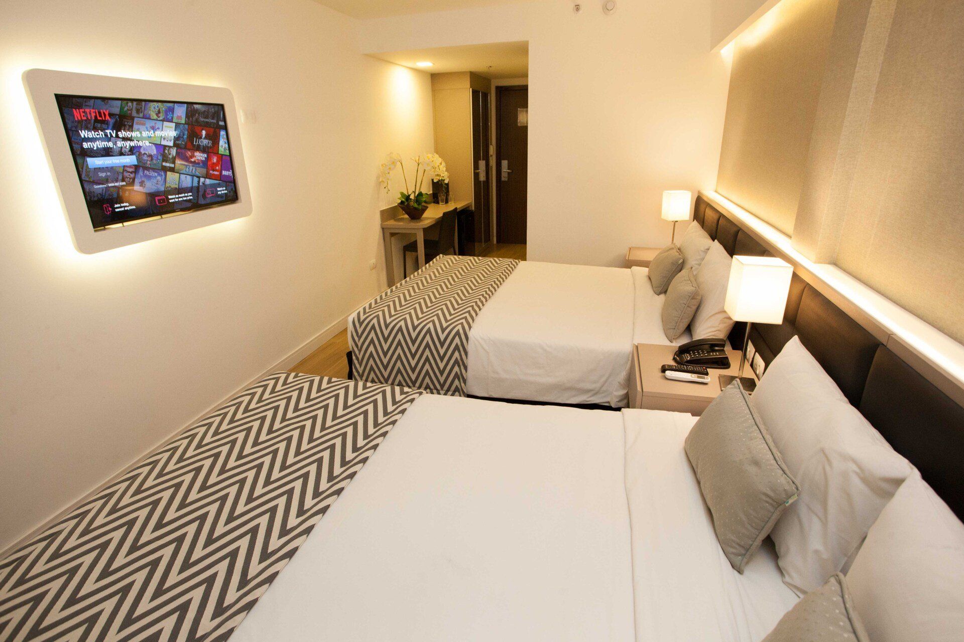 Um quarto de hotel com duas camas e uma TV de tela plana na parede.