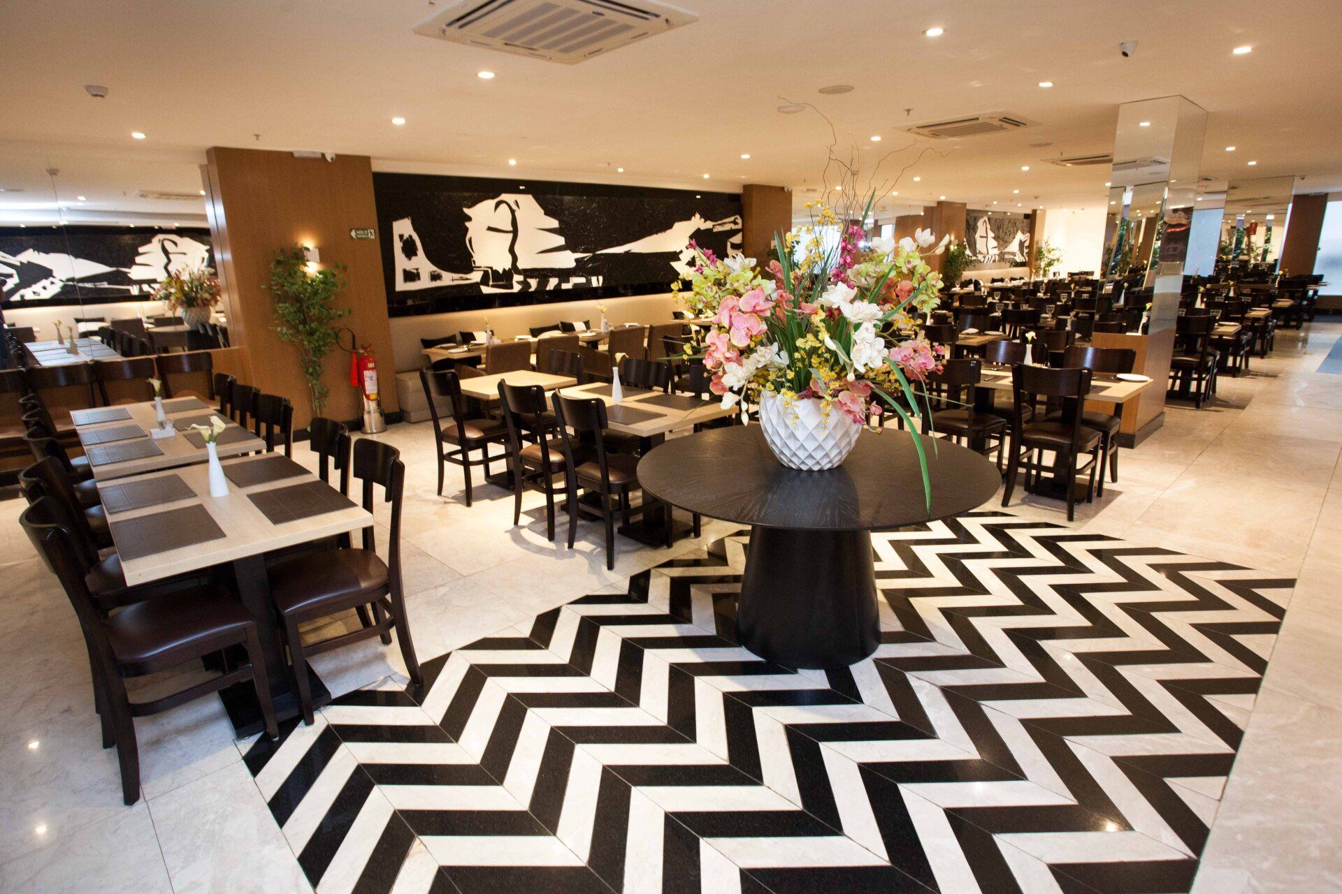 Um restaurante com mesas e cadeiras e um piso em zigue-zague preto e branco
