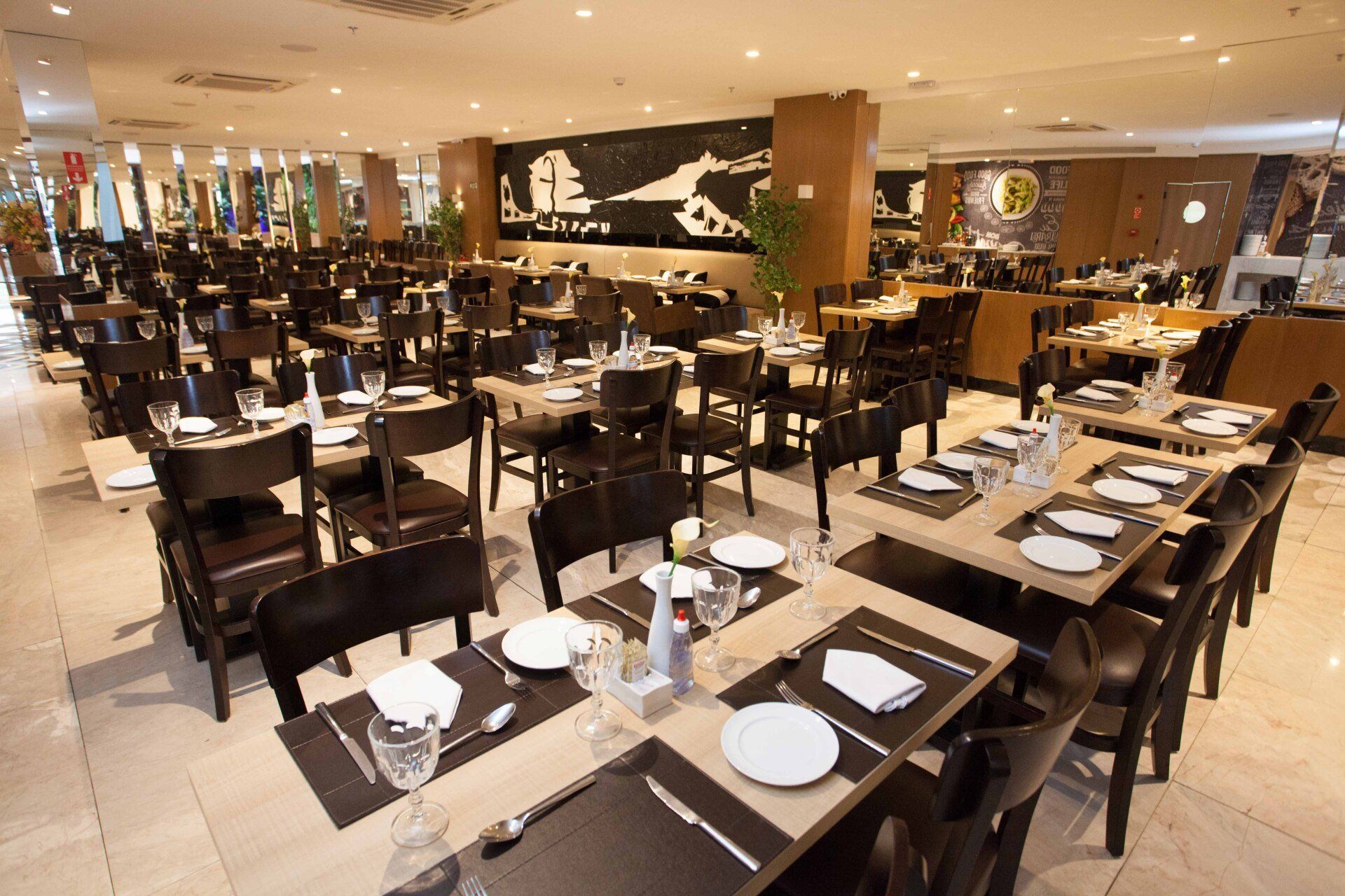 Uma grande sala de jantar com mesas e cadeiras preparadas para o jantar