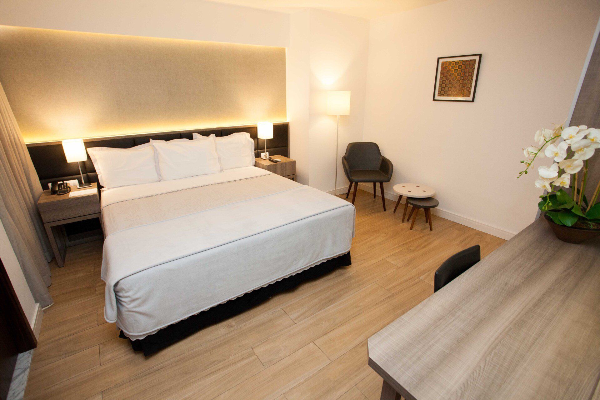 Um quarto de hotel com uma cama king size, cadeira, mesa e escrivaninha.