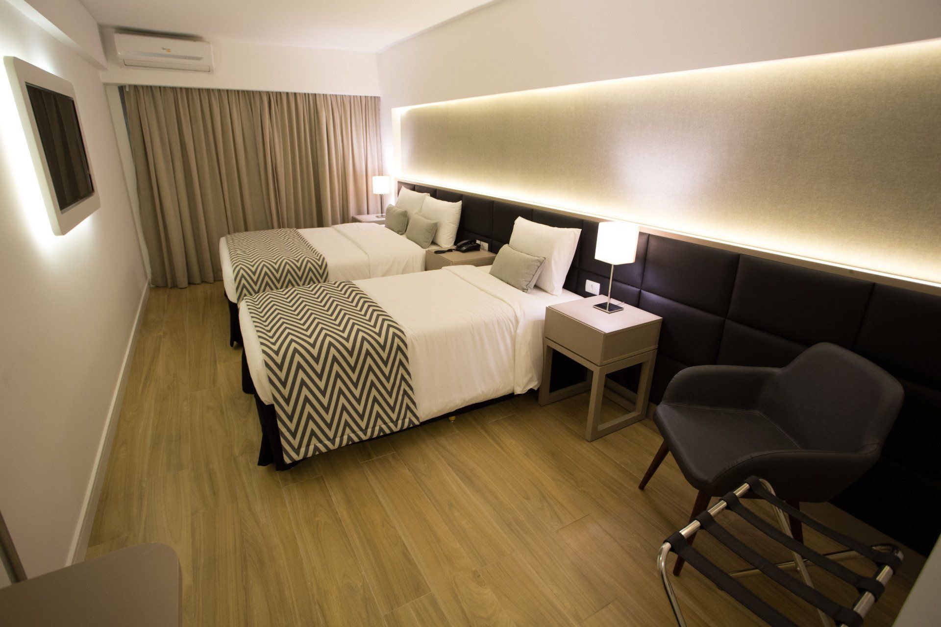 Um quarto de hotel com duas camas, uma cadeira e uma televisão.