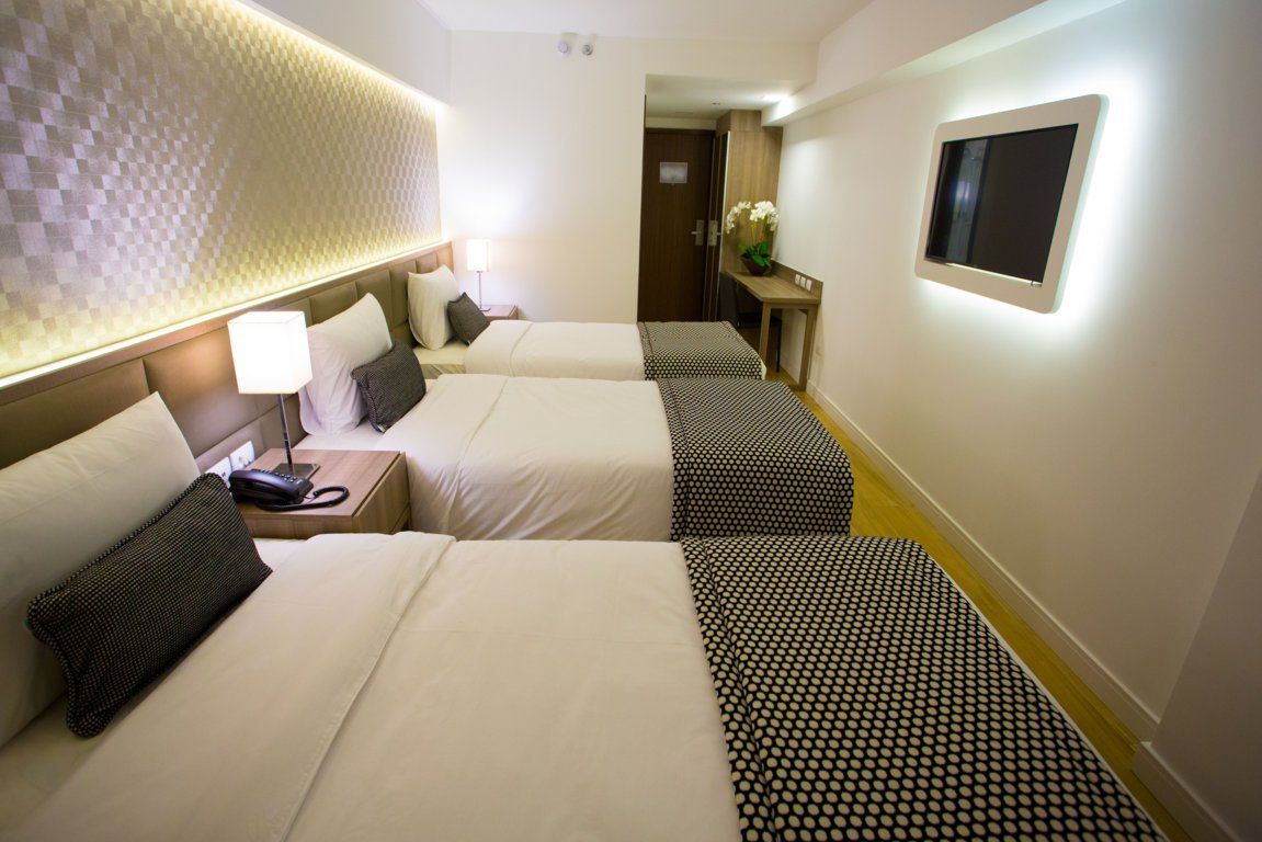 Um quarto de hotel com três camas e uma TV de tela plana.
