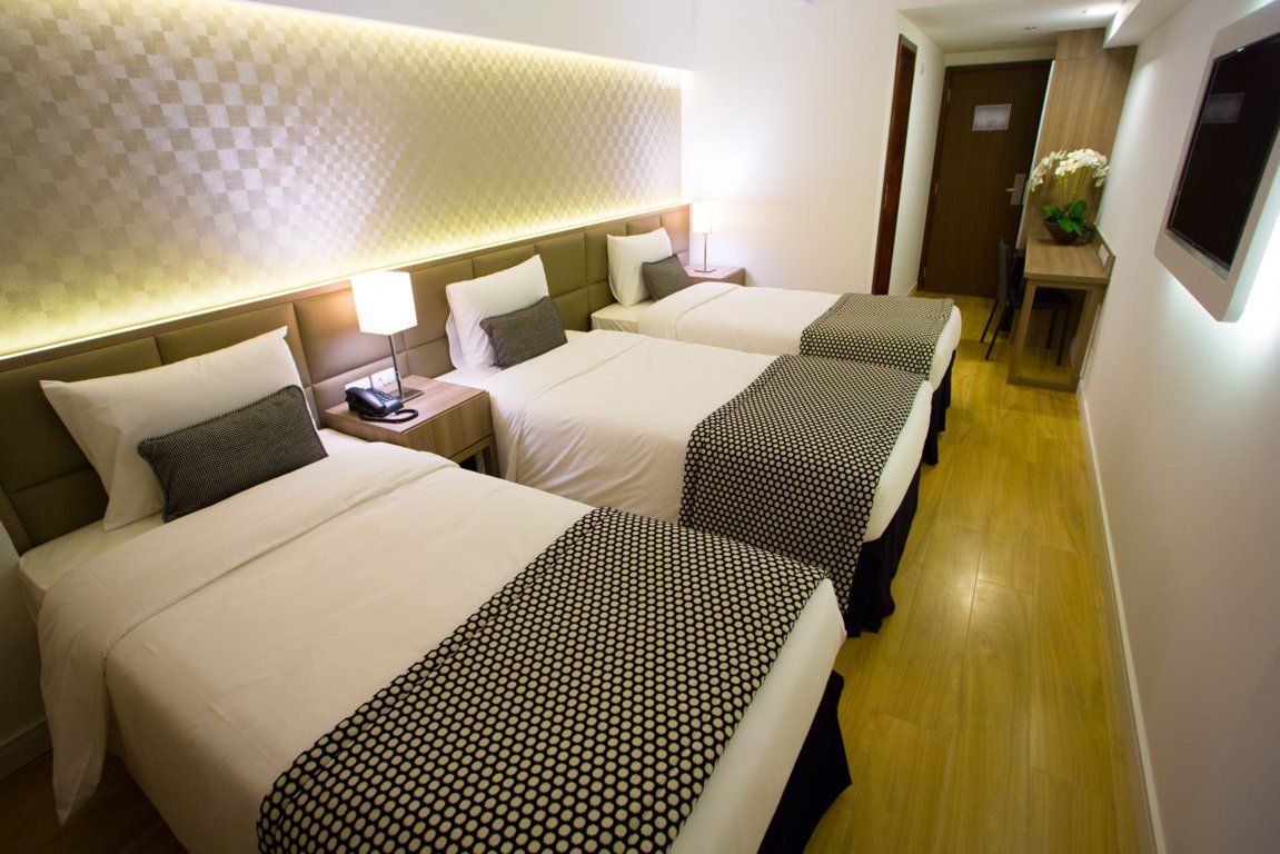 Um quarto de hotel com três camas e uma televisão