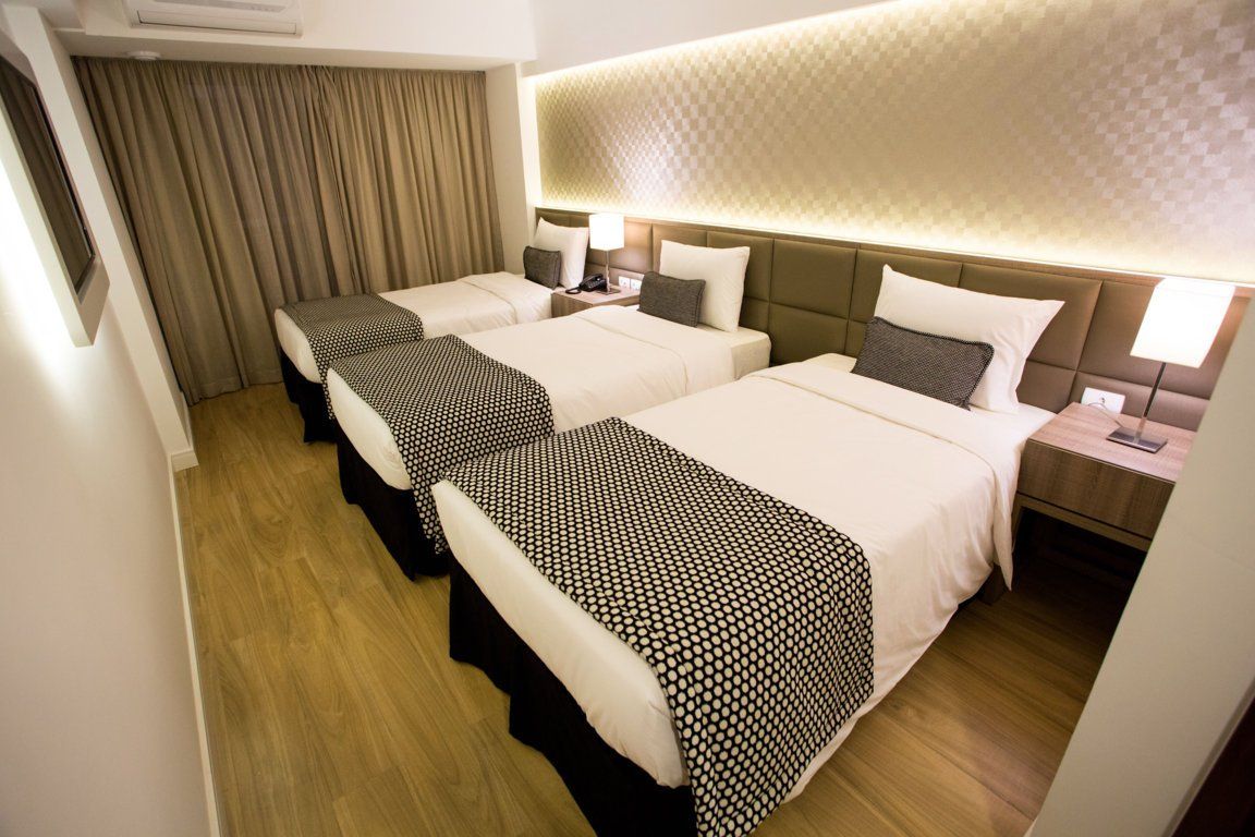 Um quarto de hotel com três camas e piso de madeira