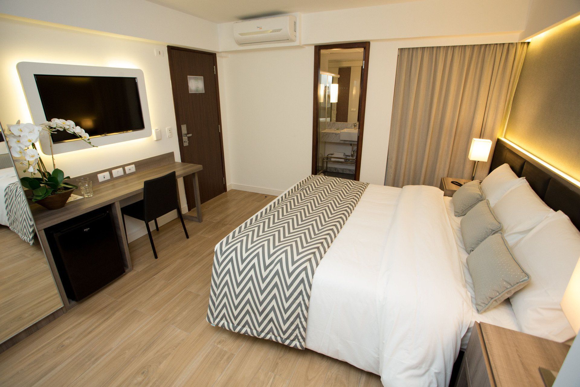 Um quarto de hotel com uma cama grande, escrivaninha e televisão.