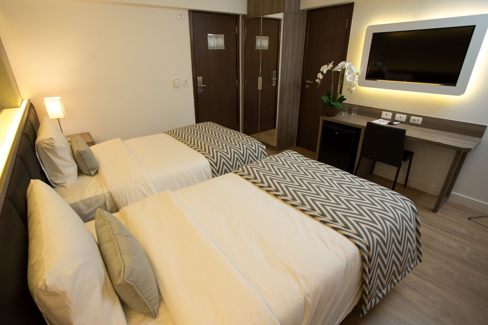 Um quarto de hotel com duas camas e uma TV de tela plana.