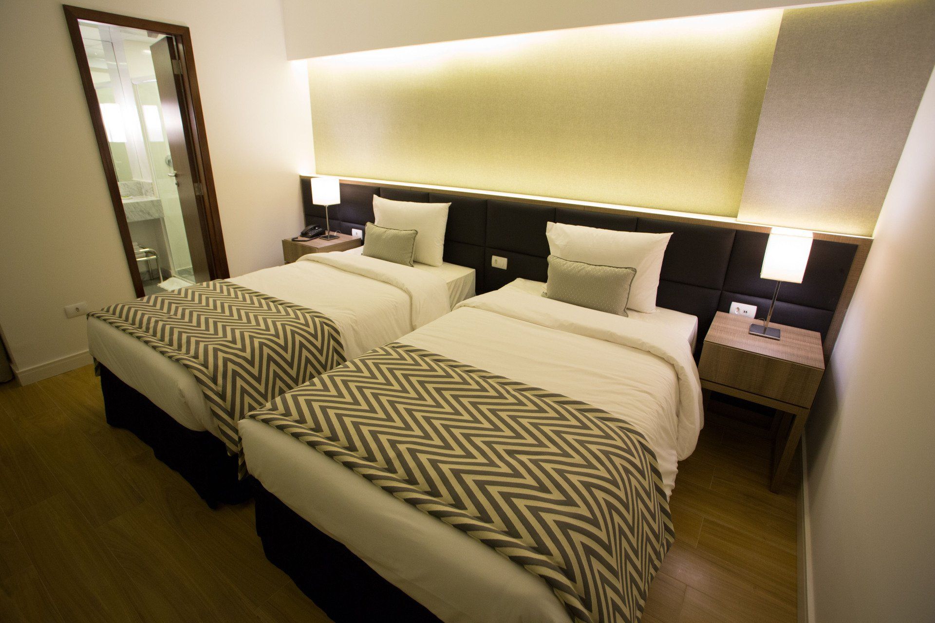 Um quarto de hotel com duas camas e um espelho.