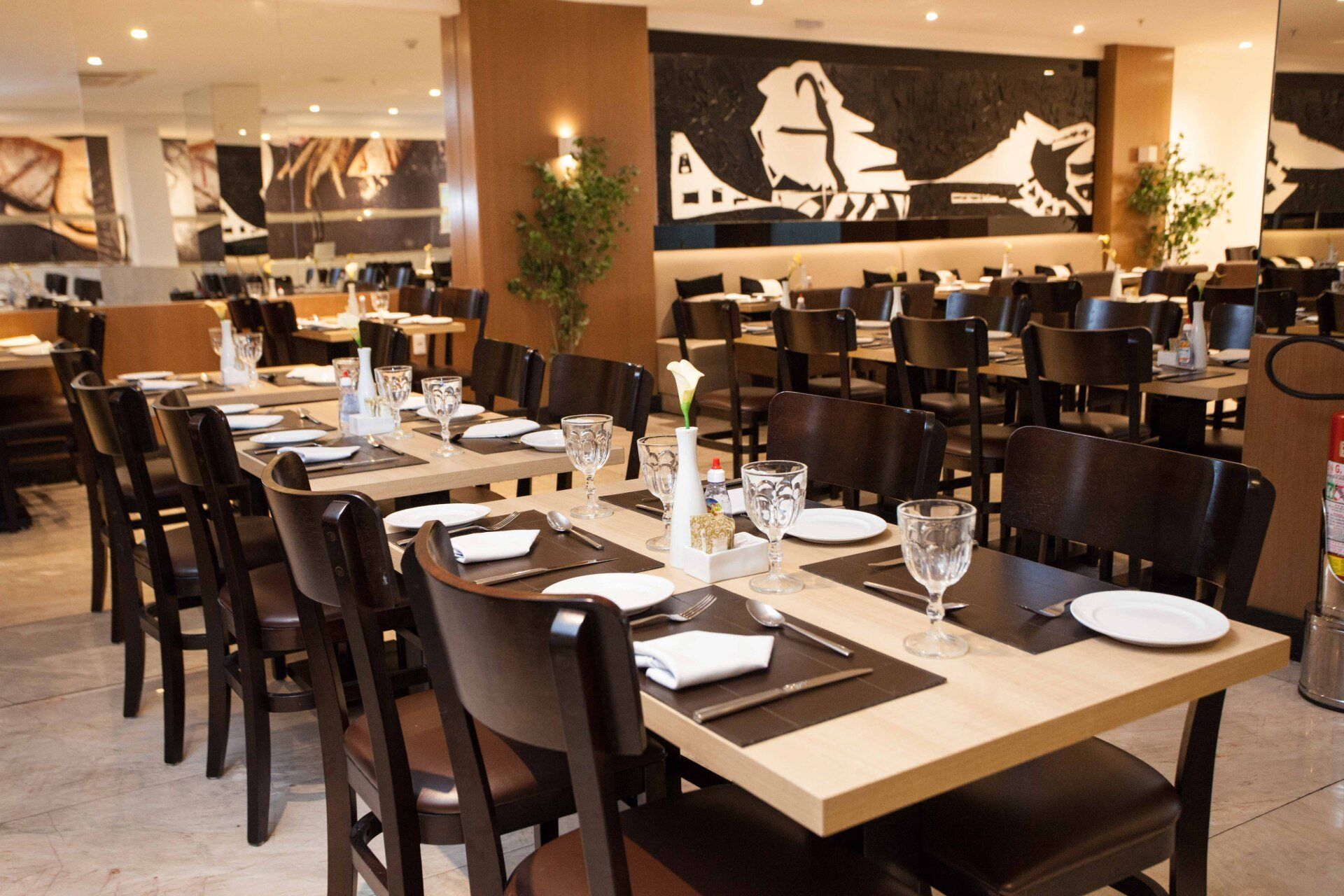 Um restaurante cheio de mesas e cadeiras com pratos e copos sobre elas